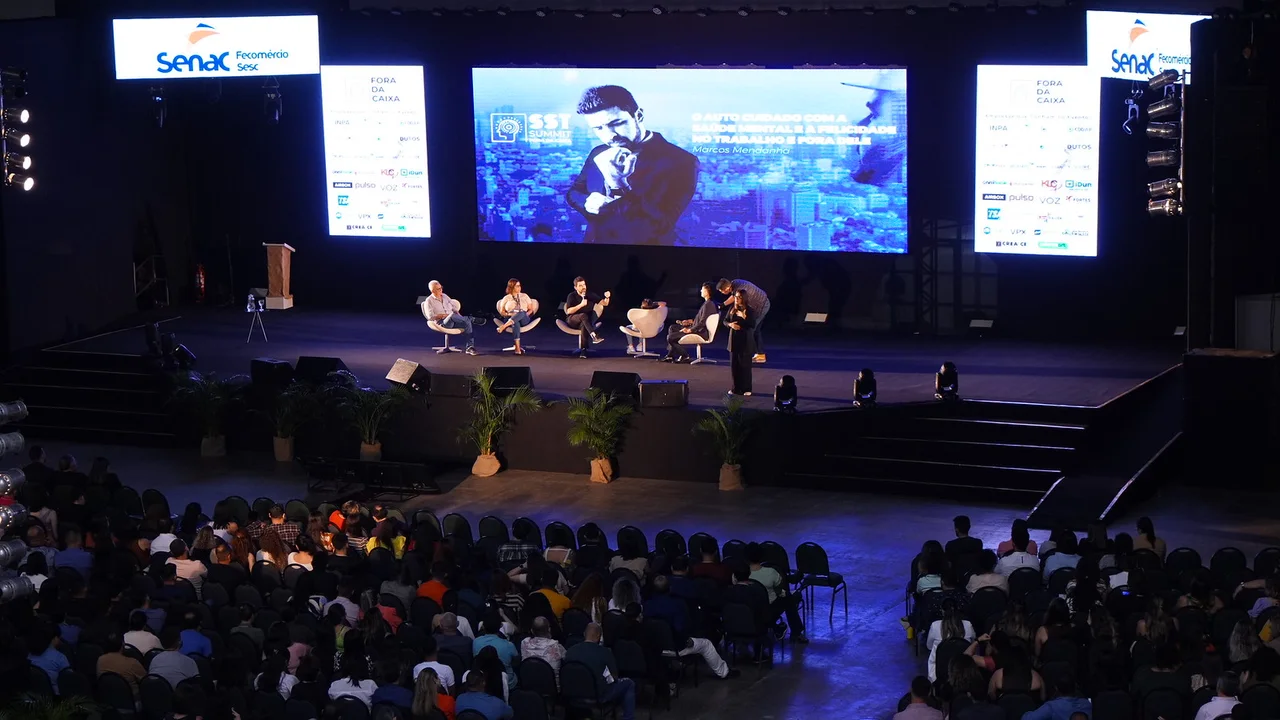 Painel de convidados sentados no palco do SST Summit conversando com a plateia